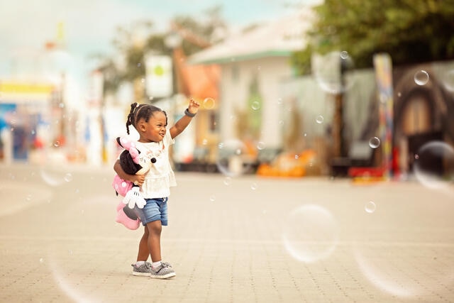 Little girl holding Mini Mouse and playing with bubbles while on vacation in Orlando, Florida. 