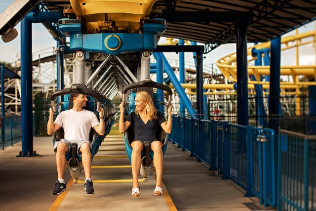 Couple smiling while sitting on a roller coaster. 