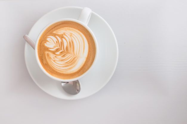 Overhead shot of coffee with coffee art on white table. 