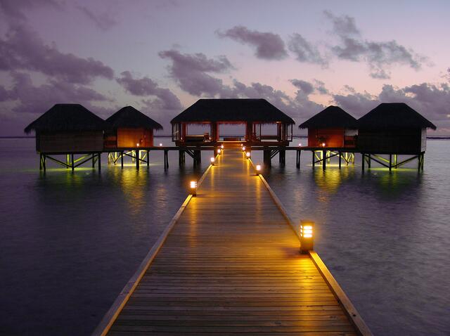 Idyllic tropical scene, overwater bungalows glowing against the dusk sky, Conrad Maldives Rangali Island. 