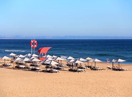 Umbrellas for beachgoers at Carcavelos Beach near Lisbon, Portugal, with a view of the ocean