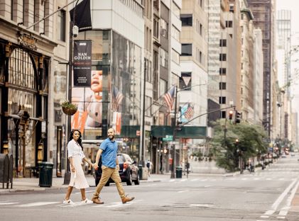 A couple holds hands as they cross the street in New York City