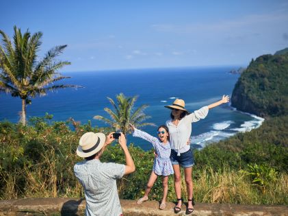 A mother and daughter pose for a photo along a Hawaiian coast