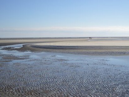 Two people in the distance walk on the beach of St. Simons Island, Georgia