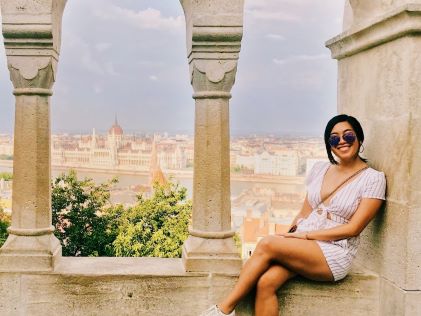 A Hilton Grand Vacations Member posing by stone windows looking out on a city