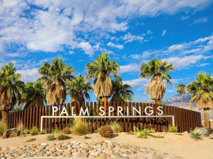 A white lettered sign of "Palm Springs" with palm trees in California