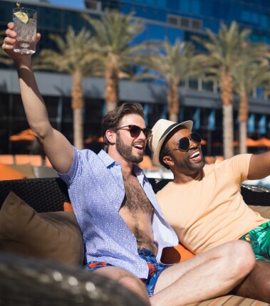 Male couple in sunglasses enjoying their vacation by the palm trees