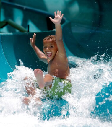 Child coming down a waterslide with hands up